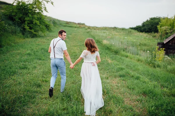 Boldog menyasszony és a vőlegény a zöld fűben járás — Stock Fotó