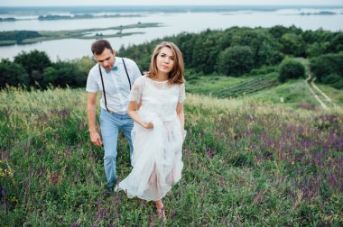 Mutlu gelin ve damat yeşil çimenlerin üzerinde yürüyüş
