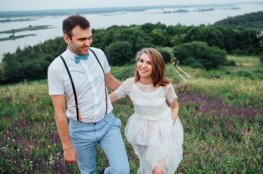 Mutlu gelin ve damat yeşil çimenlerin üzerinde yürüyüş