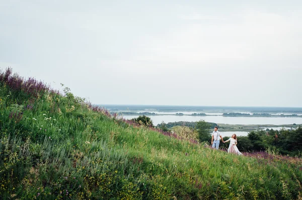 Gelukkige bruid en bruidegom lopen op het groene gras — Stockfoto