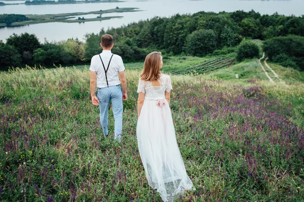 Gelukkige bruid en bruidegom lopen op het groene gras — Stockfoto