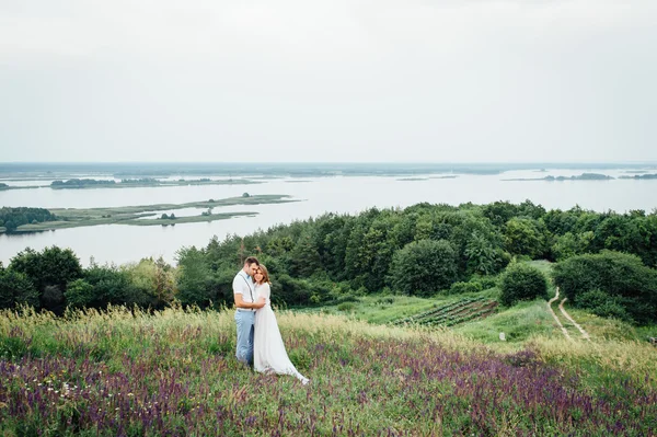 Gelukkige bruid en bruidegom lopen op het groene gras — Stockfoto