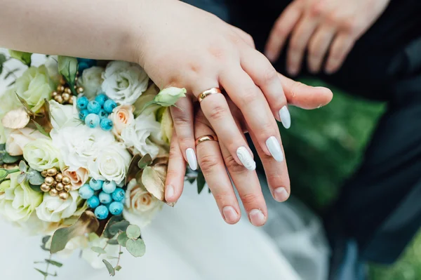 Руки і кільця на весільний букет крупним планом — стокове фото