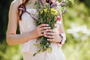 Kır çiçekleri parkta tutan hamile kadın