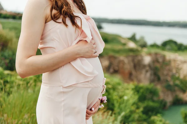 Açık havada rahatlatıcı pembe elbiseli hamile kadın — Stok fotoğraf