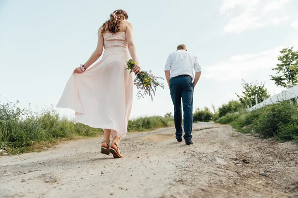 Mujer embarazada caminando con flores — Foto de Stock