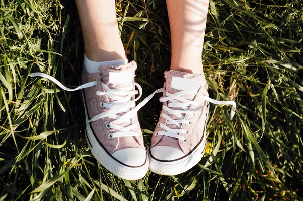 Lila sneakers på flicka ben på gräs — Stockfoto