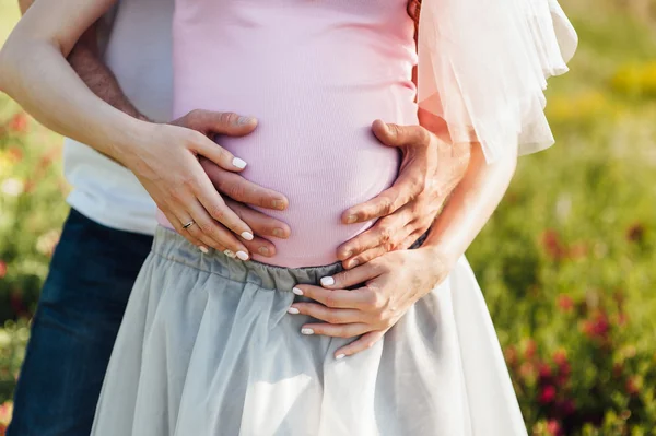 Glückliches und junges schwangeres Paar beim Umarmen — Stockfoto