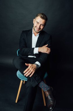 Fotoğraf stüdyosunda sandalyede oturan yakışıklı iş adamı.