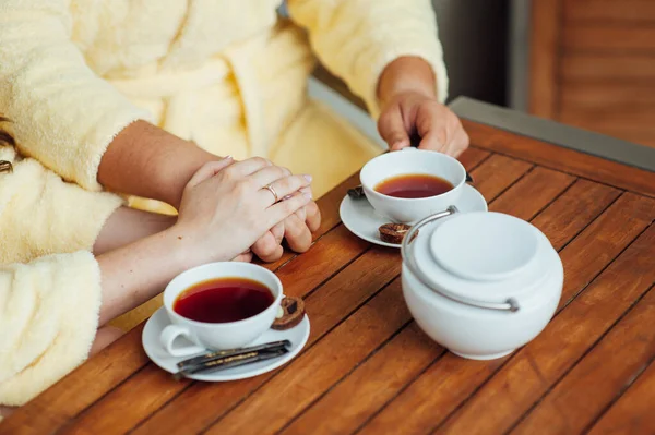 Una pareja amorosa se sienta en batas y bebe té en una mesa de madera — Foto de Stock