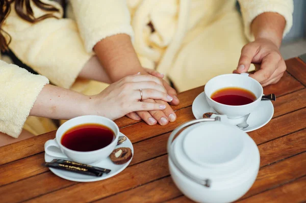 Una pareja amorosa se sienta en batas y bebe té en una mesa de madera — Foto de Stock