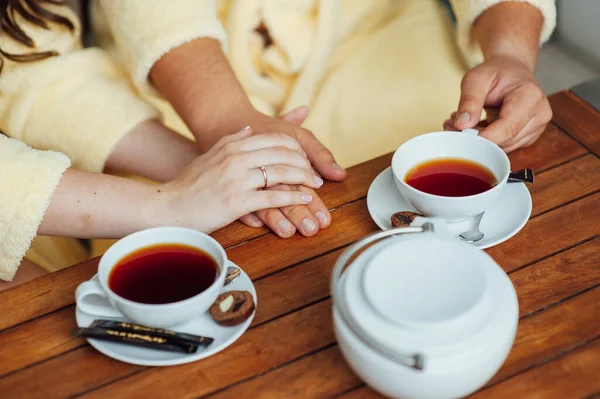 Una pareja amorosa se sienta en batas y bebe té en una mesa de madera — Foto de Stock