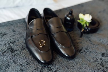 Düğün sabahı. Damat aksesuarları gri yatak örtüsünde yatıyor.