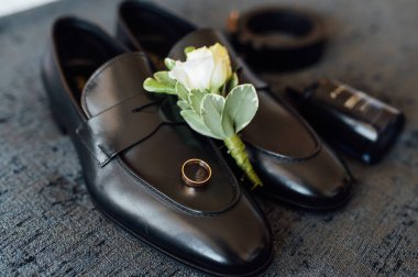 Düğün sabahı. Damat aksesuarları gri yatak örtüsünde yatıyor.