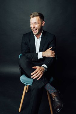 Fotoğraf stüdyosunda sandalyede oturan yakışıklı iş adamı.