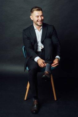 Fotoğraf stüdyosunda sandalyede oturan yakışıklı iş adamı.