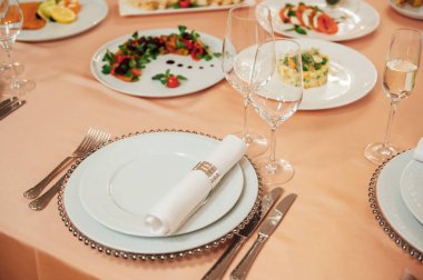 Lüks restoran. Lüks içecekler, beyaz masalar, misafirler için servis tabakları ve bardaklar.