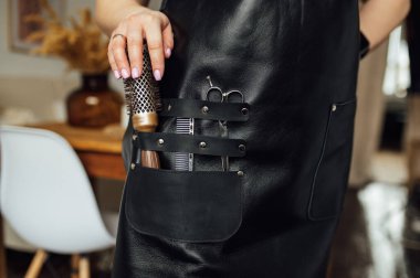 Siyah önlüklü, siyah arka planda profesyonel kuaförü olan, yakın plan.