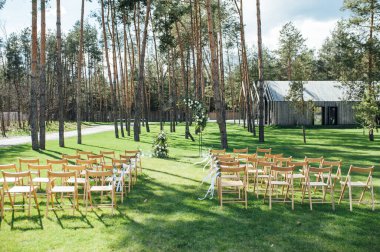 Dışarıda çok güzel bir tören. Ormanda klasik düğün. Çiçekli metal kemer.