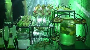 Eğlenceli bir parti için çeşitli atıştırmalıklar ve içecekler. Büfe masası. Yeşil neon ışığı