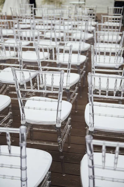 Glass chairs stand in a row in a beautiful wedding outing ceremony — Stock Photo, Image