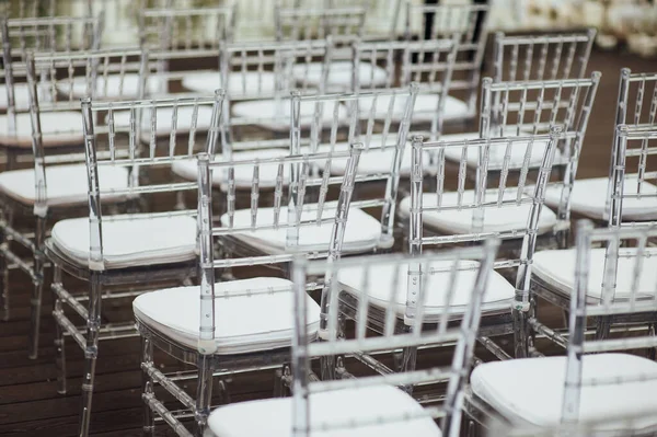 Glass chairs stand in a row in a beautiful wedding outing ceremony — Stock Photo, Image