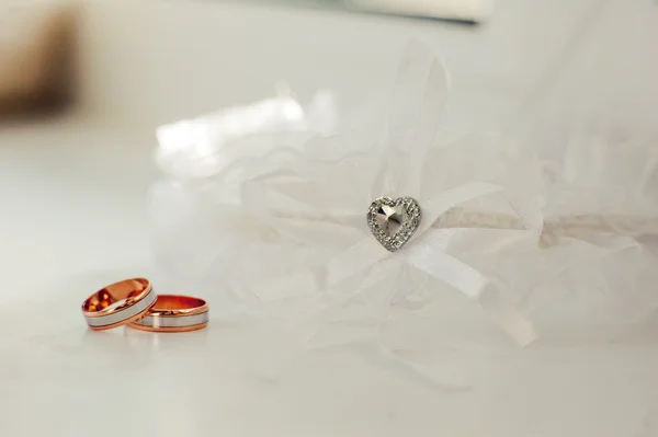 Обручальные кольца рядом с подвязкой невесты — стоковое фото