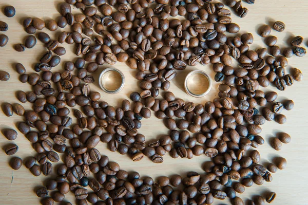 Muitos grãos de café marrom com anéis de casamento — Fotografia de Stock