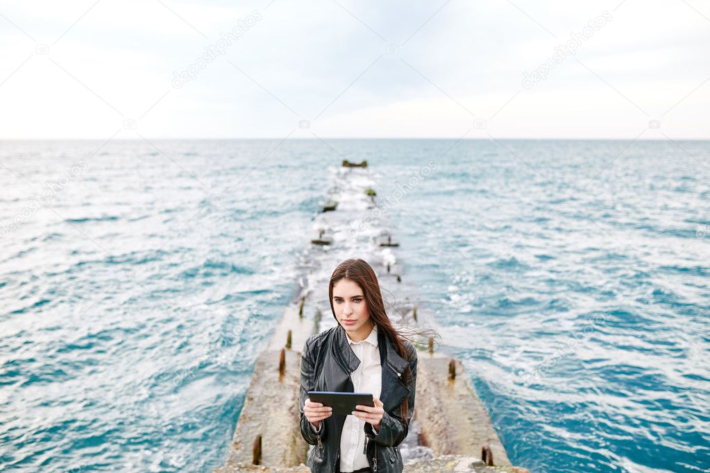 Beautiful woman on a pier with the tablet