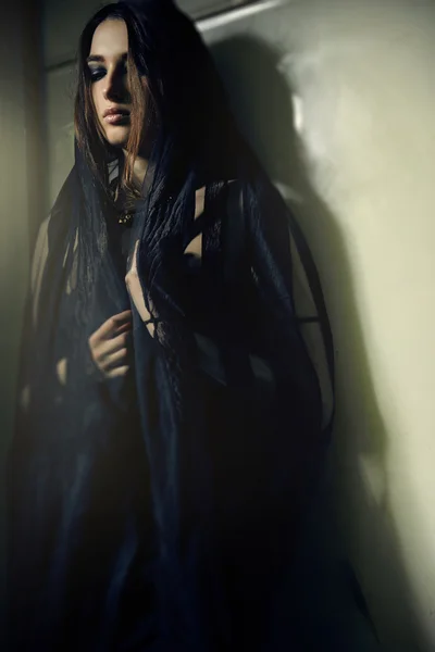 Mulher em um manto preto na parede verde — Fotografia de Stock