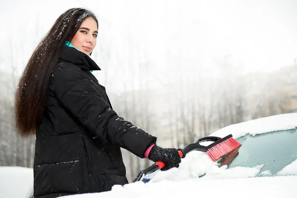 Piękna młoda kobieta, usuwanie śniegu z jej samochodu — Zdjęcie stockowe