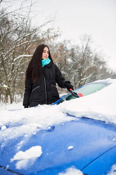 Vacker ung kvinna att ta bort snö från hennes bil — Stockfoto