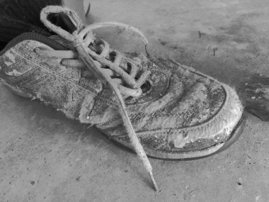 Çimento siyah beyaz zemin üzerinde bir kirli eski spor ayakkabı