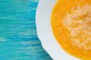 Balkabağı çorbası ekşi krema ve tohumlar ahşap bir turkuaz masa üzerinde. Seçici odak, hareketsiz yaşam, yiyecek ve içecek konsepti. 