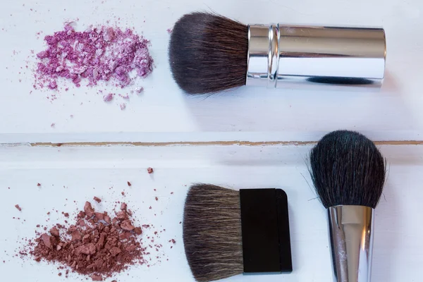 Accesorios cosméticos de las mujeres. Pinceles de maquillaje y sombra de ojos aplastada sobre fondo de madera —  Fotos de Stock