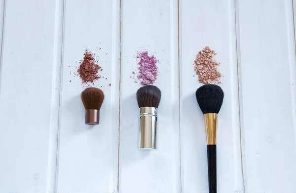 Accessoires cosmétiques pour femmes. Pinceaux de maquillage et fard à paupières broyé sur fond bois — Photo