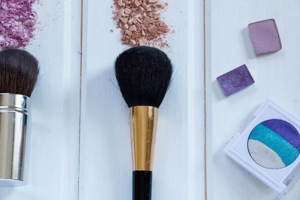 Dla kobiet akcesoria kosmetyki. Pędzle do makijażu i pokruszony cień do powiek na drewniane tła — Zdjęcie stockowe