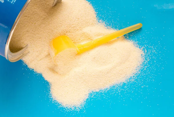 Powdered Milk, Baby Formula with spoon infant formula in can and bottle for feeding baby on blue wooden table. dairy food for baby  spilling out of a measuring scoop.