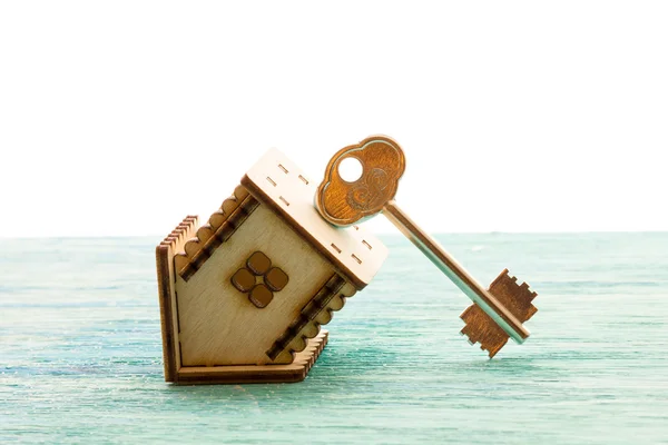 Παιχνίδι ξύλινος μοντέλο σπίτι ως σύμβολο οικογένεια και αγάπη έννοια για το ηλιόλουστο παλιό μπλε ξύλινο φόντο αγοράζοντας ένα σπίτι, υποθήκη, επισκευή, σταθερότητα τα κλειδιά ανάποδα, ανάποδα — Φωτογραφία Αρχείου