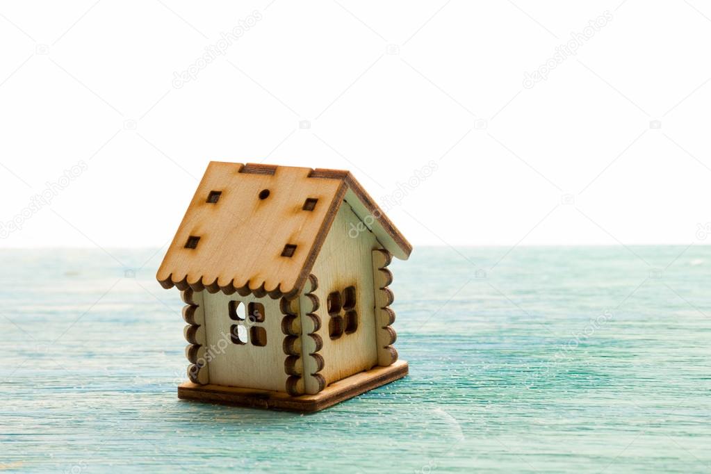 toy wooden model house as symbol family and love concept  on sunny old blue wooden background buying a house, mortgage, repair, stability