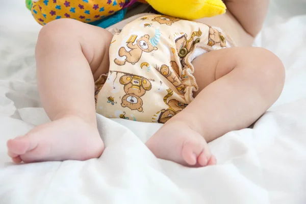 Baby in modern eco stacks of cloth diapers and replacement bushings selective focus close-up on bright background — Stock Photo, Image