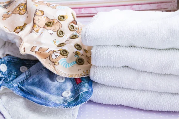 Modern eco stacks of cloth diapers and replacement bushings selective focus close-up on bright background — Stockfoto