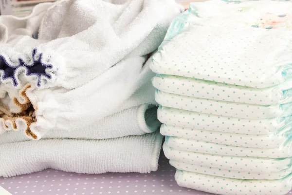Modern eco stacks of cloth diapers and disposable diapers, pampers, selective focus close-up on bright background — Stock Photo, Image