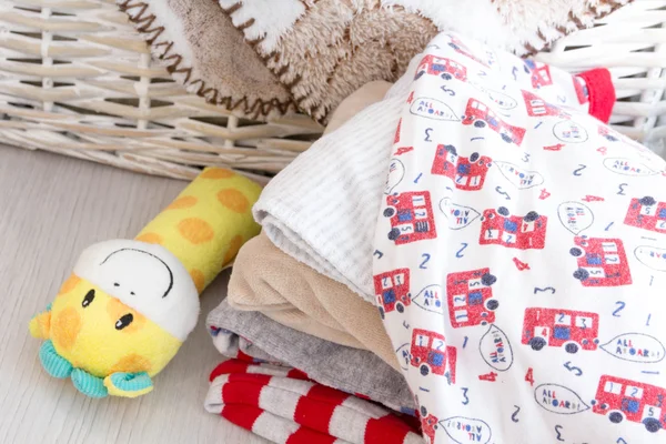 grey basket with children's toys, diapers, accessories on table on grey wooden background. Mother care. children's room, the pile of blue clothes for newborn boy