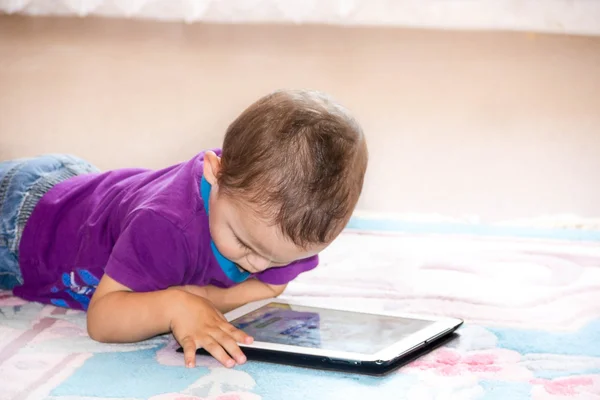 Chłopiec dziecko siedzi na podłodze gry z komputera typu tablet. Trochę panel dotykowy, wczesna nauka. — Zdjęcie stockowe