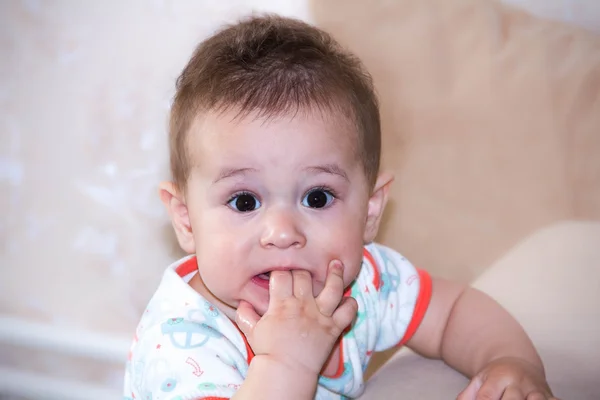 Kisfiú játszik ujjával a száj és a boldog arc kifejezése. Portréja egy csúszó mosolyogva. Fogzás csecsemő játszik. Újszülött gyermek otthon. A karcolás a fogát. — Stock Fotó