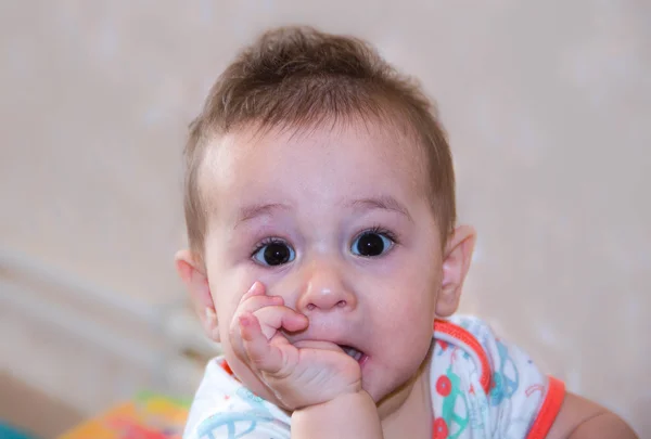 Babyjongen speelt met de vingers in de mond en gelukkig gelaatsuitdrukking. Portret van een kruipende glimlachen. Tandjes baby spelen. Pasgeboren kind thuis. De krassen zijn tanden. — Stockfoto
