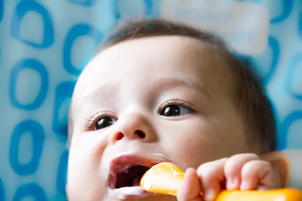 Pequeño niño feliz sentado en una silla y come yogur de cuya cara está manchado en la comida para bebés — Foto de Stock