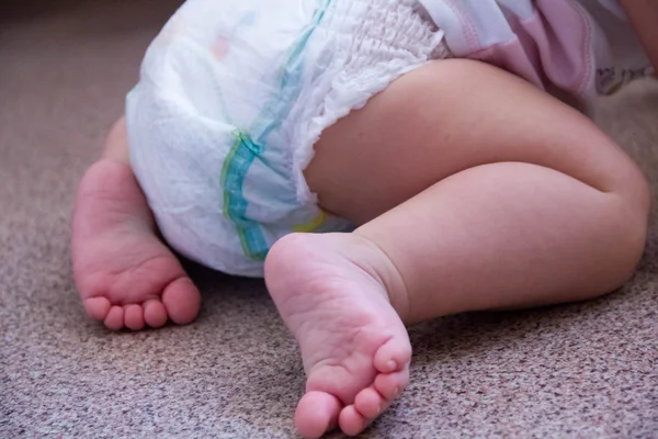 Baby in modern diapers and replacement bushings selective focus close-up on bright background — Stock Photo, Image