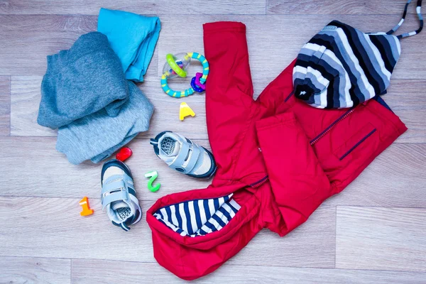 Ropa de invierno bebé, concepto, otoño, zapatillas de deporte, gorras, juguetes. cómo vestir al bebé en invierno. elegir los zapatos . — Foto de Stock